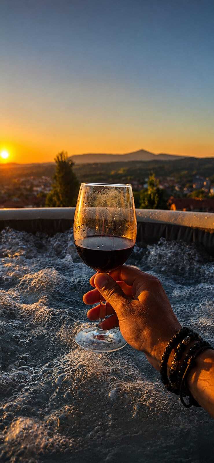 Čaša vina u jacuzziju sa pogledom na zalazak